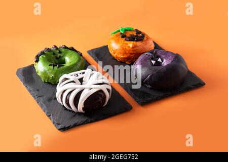 Assortmen von Halloween Donuts auf orangefarbenem Hintergrund Stockfoto