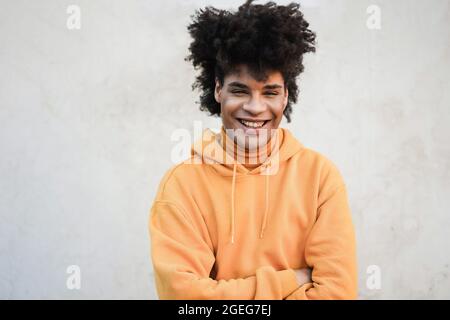 Junger Mann mit gemischter Rasse, der in der Stadt vor der Kamera lächelt - Fokus auf Gesicht Stockfoto