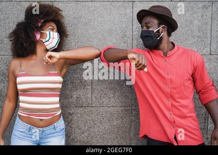 Afrikanische Menschen tragen Gesichtsmasken, während sie ihre Ellbogen anstoßen, anstatt Grüße mit Umarmungen - Fokus auf Gesichter Stockfoto