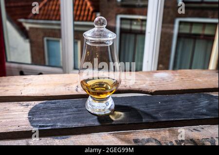 DRAM von Single Malt Scotch Whisky serviert in Probierglas mit Blick auf alte Fenster und Häuser auf gebrauchte Holzkiste Stockfoto