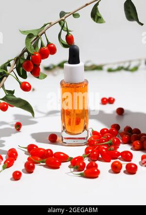 Goji-Beerensamenöl in Glasflasche und frische Goji-Beeren auf dem Tisch. Stockfoto