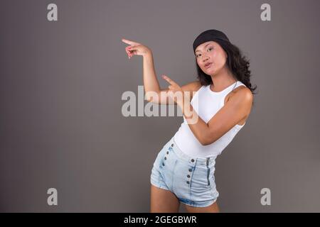 chinesisches Mädchen mit Bandana und isoliertem T-Shirt, das auf die Seite zeigt und etwas zeigt. Stockfoto