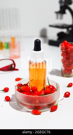 Goji-Beerensamenöl in Glasflasche und frische Goji-Beeren auf dem Tisch. Stockfoto