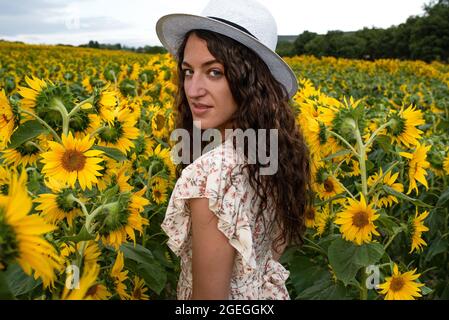 Junge Frau, die mitten auf einem Sonnenblumenfeld steht Stockfoto