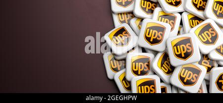 Die Logos der Versand- und Empfängerfirma UPS United Parcel Service auf einem Haufen auf einem Tisch. Speicherplatz kopieren. Webbanner-Format. Stockfoto