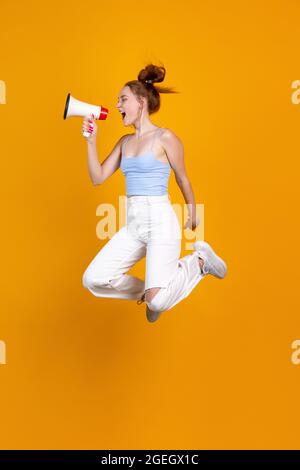 Vertikales Bild von jungen niedlichen Mädchen springen isoliert auf gelben Studio-Hintergrund. Weibliches Modelmodell in legerer Kleidung. Konzept der menschlichen Emotionen Stockfoto