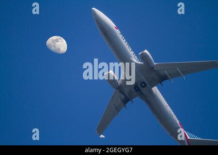 Ein Passagierjet der Boeing 737 von American Airlines geht kurz nach dem Start mit einem zunehmenden, schwungvollen Mond über dem Flugzeug nach unten. Stockfoto