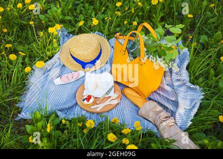 Picknick im Park auf der Wiese: Tischdecke, Tasche, Hut, Sire, Erdbeere, Baguette, Ansicht von oben. Stockfoto