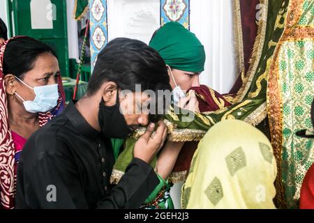 Dhaka, Bangladesch. August 2021. Schiitische Muslime aus Bangladesch küssen die Flagge mit gestickten Gebeten.Aschura ist der zehnte Tag von Muharram, dem ersten Monat des islamischen Kalenders, der weltweit zum Gedenken an das Martyrium von Imam Hussain, dem Enkel des Propheten Muhammad, beobachtet wird. Kredit: SOPA Images Limited/Alamy Live Nachrichten Stockfoto