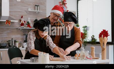 Großeltern Kaffee Enkelkind machen traditionelle weihnachten hausgemachte Kekse feiern Feiertage. Kind mit Nudelholz Zubereitung Lebkuchenteig Dessert mit Backwaren Cookie Zutaten Stockfoto