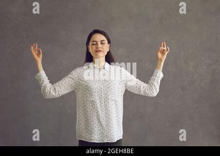 Frau mit geschlossenen Augen meditiert entspannt und hält ruhige Studioaufnahmen Stockfoto