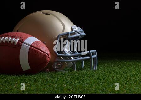 Low-Angle-Ansicht von Fußball und Gold Helm auf Gras mit dunklem Hintergrund Stockfoto