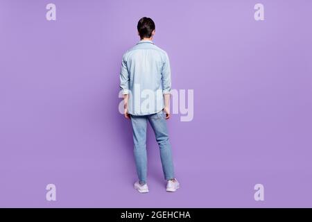 Zurück Rückansicht in voller Länge Foto von jungen Kerl anonym Inkognito Wirbelsäule Denim Kleidung isoliert über lila Farbe Hintergrund Stockfoto