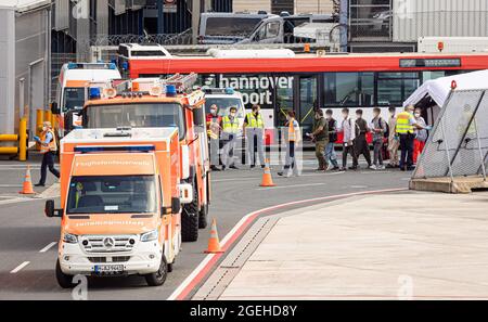 Langenhagen, Deutschland. August 2021. Menschen laufen über das Gelände des Flughafens Hannover-Langenhagen, vorbei an Einsatzfahrzeugen der Feuerwehr und Rettungsdienste. Mehr Menschen, die aus Afghanistan in Sicherheit gebracht wurden, kamen mit einem Flugzeug an, das aus der usbekischen Hauptstadt Taschkent abgeflogen war. Quelle: Moritz Frankenberg/dpa/Alamy Live News Quelle: dpa picture Alliance/Alamy Live News Stockfoto
