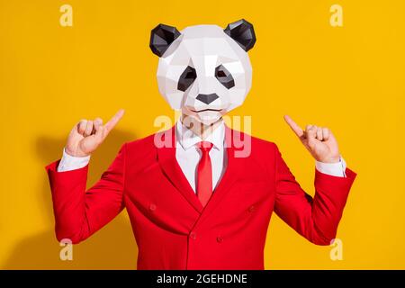 Foto von Promoter Freak Kerl zeigen Finger Kopf tragen Panda Maske roten Anzug isoliert auf gelbem Hintergrund Stockfoto