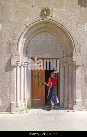 Frau mit Kapellenschleier, die in die Katoghike-Kirche (Kathedrale) des mittelalterlichen Kecharis-Klosterkomplexes in der Stadt Tsakhkadzor, Armenien, eintritt Stockfoto