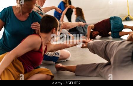 Tänzer berühren Hände und Füße in Kontaktimprovisation vor dem Hintergrund einer Jam-Performance, die absichtlich mit Bewegungsunschärfe und Defokussierbokeh aufgeht Stockfoto