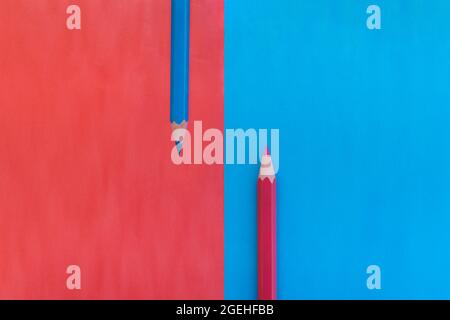 Rosa und blauer Hintergrund vertikal geteilt mit zwei passenden Farbstiften auf gegenüberliegenden Farben platziert. Draufsicht flach liegend mit Platz für Text Stockfoto