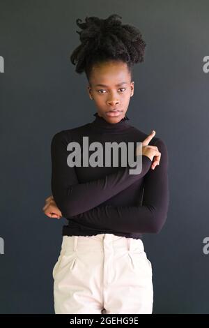 Junge afrikanerin in schwarzem Pullover auf schwarzem Hintergrund. Stockfoto