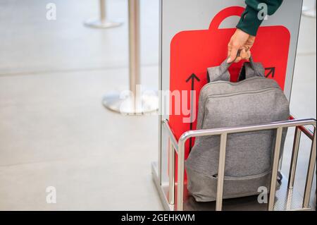 Frau überprüft den Metallkäfig des Rucksacks und kontrolliert das Handgepäck am Flughafen. Stockfoto