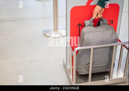 Frau überprüft den Metallkäfig des Rucksacks und kontrolliert das Handgepäck am Flughafen. Stockfoto