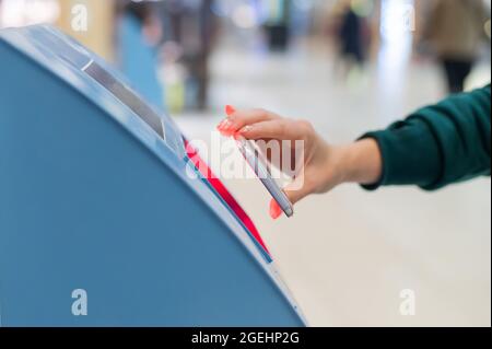 Eine gesichtslose Frau scannt den qr-Code von ihrem Smartphone aus. Ein Mädchen nutzt am Flughafen einen Self-Service-Automaten, um für einen Flug einzuchecken und Tickets auszudrucken Stockfoto