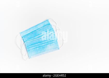 Chirurgische Maske mit Gummi-Ohrbändern. Typische 3-lagige OP-Maske zur Abdeckung von Mund und Nase. Schutzkonzept. Stockfoto