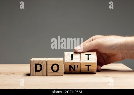 Männliche Hand drehen Holzwürfel, Block und ändern Sinn des Wortes TUN ES. Konzeptionelles Bild über Menschenrechte, Bildung, soziale Fragen, psychische Gesundheit Stockfoto