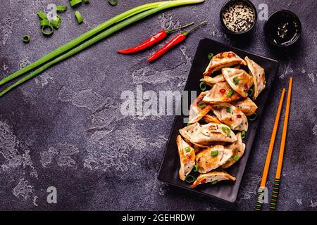 Gebratene Knödel serviert mit grünen Zwiebeln, Sesam und Chilischoten, Draufsicht Stockfoto