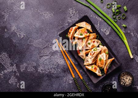 Gebratene Knödel serviert mit grünen Zwiebeln, Sesam und Chilischoten, Draufsicht Stockfoto