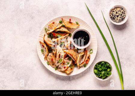 Gebratene Knödel serviert mit grünen Zwiebeln, Sesam und Chilischoten, Draufsicht Stockfoto