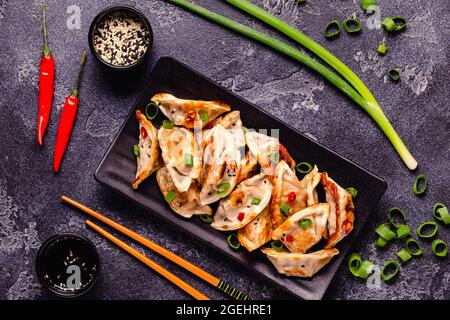 Gebratene Knödel serviert mit grünen Zwiebeln, Sesam und Chilischoten, Draufsicht Stockfoto