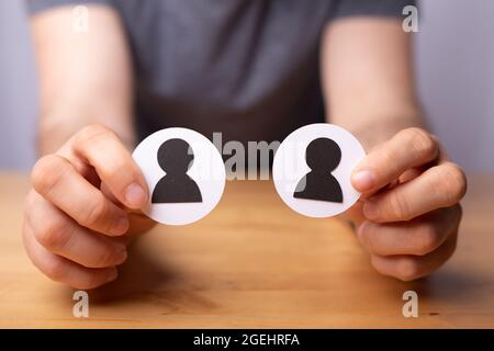 Ein Mann mit zwei Papierausschnitten von Profilikonen, die Partnerschaft und Geschäft symbolisieren Stockfoto