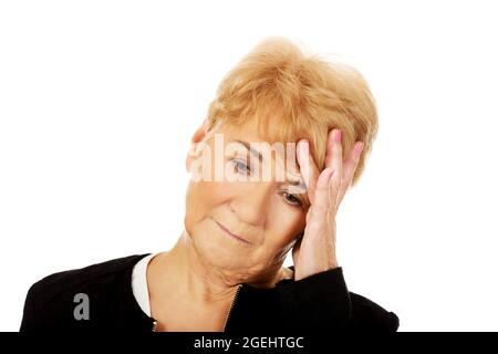 Ältere kaukasische Frau, die ihren Kopf verzweifelt hält Stockfoto