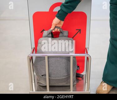 Frau überprüft den Metallkäfig des Rucksacks und kontrolliert das Handgepäck am Flughafen. Stockfoto