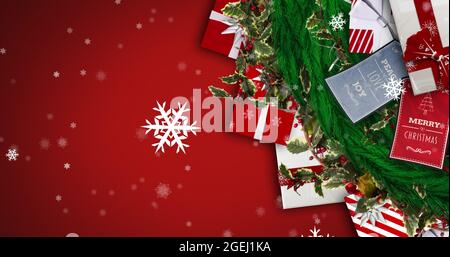 Bild von weihnachtsgeschenken und Dekorationen und Schnee fällt auf rotem Hintergrund Stockfoto