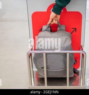 Frau überprüft den Metallkäfig des Rucksacks und kontrolliert das Handgepäck am Flughafen. Stockfoto