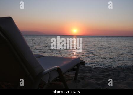 Blick auf eine Sonnenliege vor der ägäis und einen wunderschönen Sonnenuntergang im Hintergrund Stockfoto