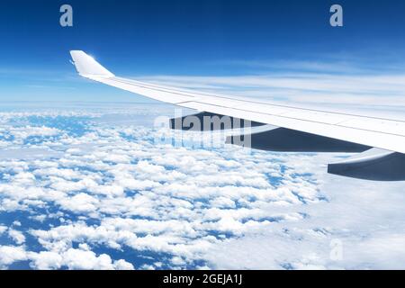 Blick auf Wolken und Flügel aus einem Flugzeugfenster. Reise- und Urlaubskonzept Stockfoto