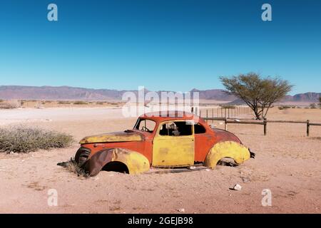 Verlassene verlassene alte Autos in der sandigen Wüste von Solitaire, Khomas Region, Namibia, mit einem blauen Himmel im Hintergrund Stockfoto