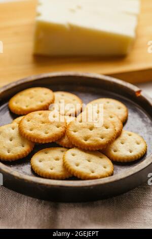 Käsekekse oder Cracker auf einem Holzteller mit Käse Stockfoto