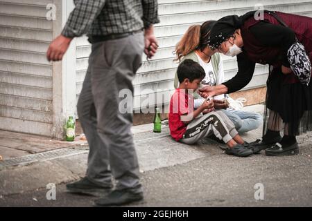 Eine türkische Frau, die als Vorsichtsmaßnahme gegen die Verbreitung von covid-19 eine Gesichtsmaske trägt, zeigt Liebe zu einem syrischen Kind, das in den Straßen des Ulus-Viertels bettelt. In der Türkei leben mehr als 4.5 Millionen Flüchtlinge. Die tatsächliche Zahl derer, die keine offizielle Registrierung haben, wird auf 8 Millionen geschätzt. Die Mehrheit besteht aus den Syrern, Afghanen, Somaliern und anderen Ländern des Nahen Ostens. Viele von ihnen arbeiten ohne legale Arbeitsgenehmigungen und werden als billige Arbeitskräfte angesehen. Die Hauptstadt Ankara beherbergt etwa 100 000 Flüchtlinge. Stockfoto