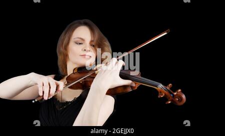 Junge Frau spielt Geige. Isoliert auf schwarzem Hintergrund. Copyspace. Stockfoto