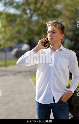 Porträt eines jungen Mannes, der auf der Straße mit dem Smartphone spricht. Geringer Fokus. Stockfoto