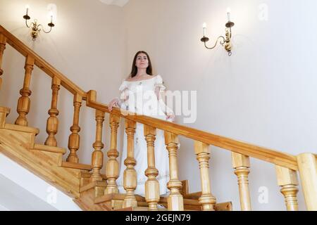 Vintage-Porträt einer jungen Frau in weißem Kleid zu Fuß die Treppe hinunter Stockfoto