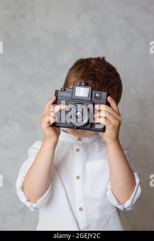 Kleiner Junge, der ein Foto mit analoger lomographie-Kamera im Vintage-Stil gemacht hat. Stockfoto