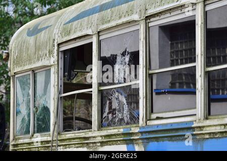 Heruntergekommener und rostiger Bus mit kaputten Fenstern in einer abgelegenen Gegend. Stockfoto