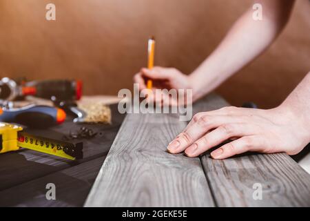 Reparatur-, Bau- und Hauskonzept - Nahaufnahme von weiblichen Händen, die Holzbretter messen. Professioneller Zimmermann misst präzise mit einem gelben t Stockfoto