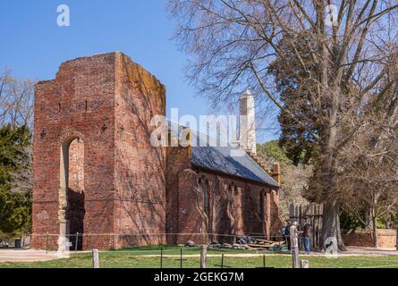 Jamestowne, VA, USA - 1. April 2013: Historische Stätte. Rote Backsteinruine des ursprünglichen Kirchturms mit Kirchenschiff im 20. Jahrhundert gegen blauen Himmel rekonstruiert w Stockfoto
