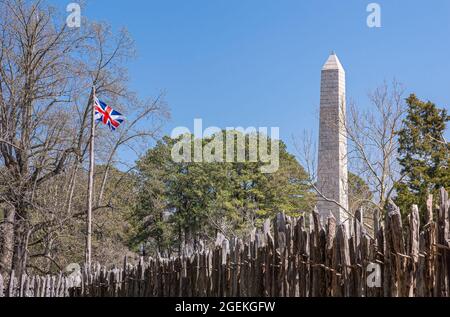 Jamestowne, VA, USA - 1. April 2013: Historische Stätte. Tencentennial Obelisk-Denkmal über Verteidigungsmauer von Fort gegen blauen Himmel gesehen. Etwas grünes Laub Stockfoto